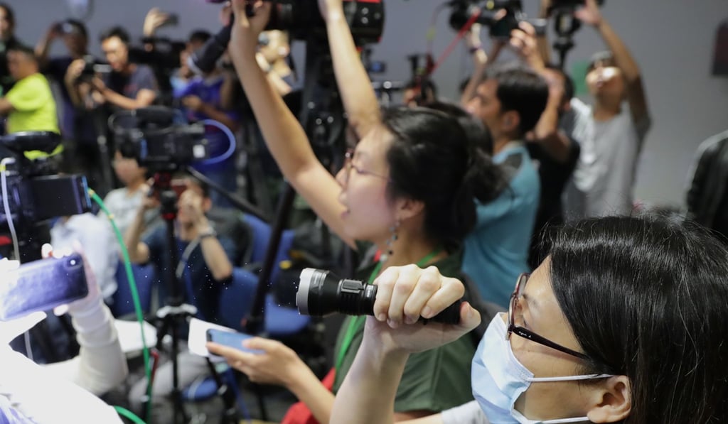 Journalists shine flashlights at the police during a press conference at the police headquarters in Wan Chai on Monday. Photo: Edmond So