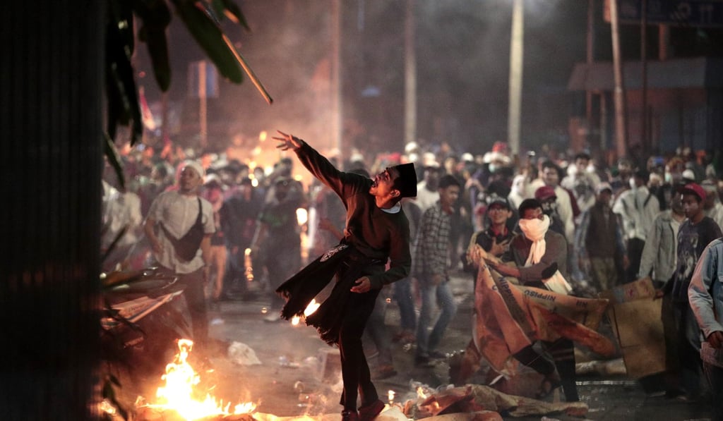 A rioter throws a stick at police during clashes in Jakarta on May 22. Photo: AP