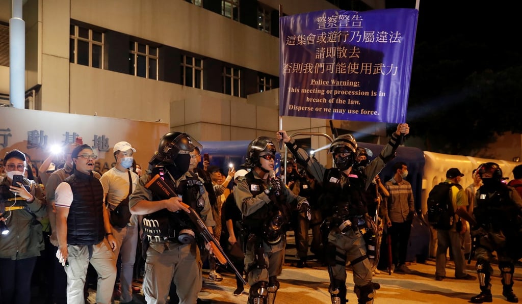 A police officer holds a banner warning protesters to disperse. Photo: Reuters A police officer holds a banner warning protesters to disperse. Photo: Reuters