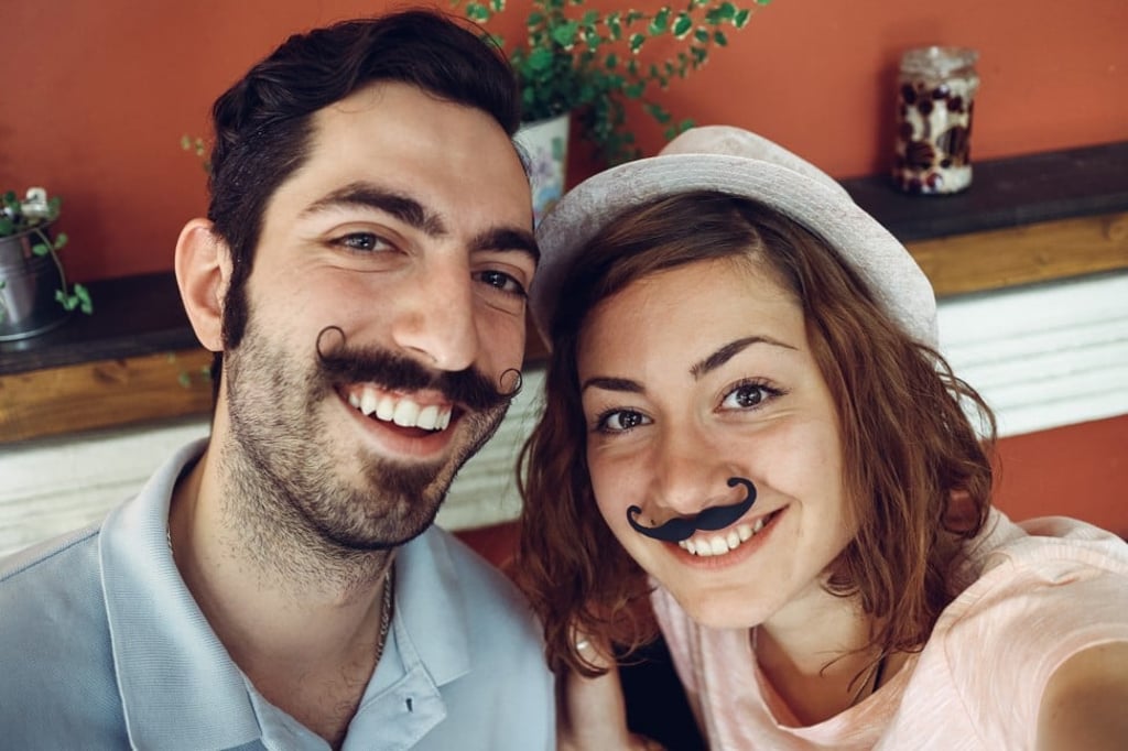 Young mustachioed couple – the woman wearing a fake –taking a selfie in celebration of Movember, which spotlights men’s health issues. Young mustachioed couple – the woman wearing a fake –taking a selfie in celebration of Movember, which spotlights men’s health issues.