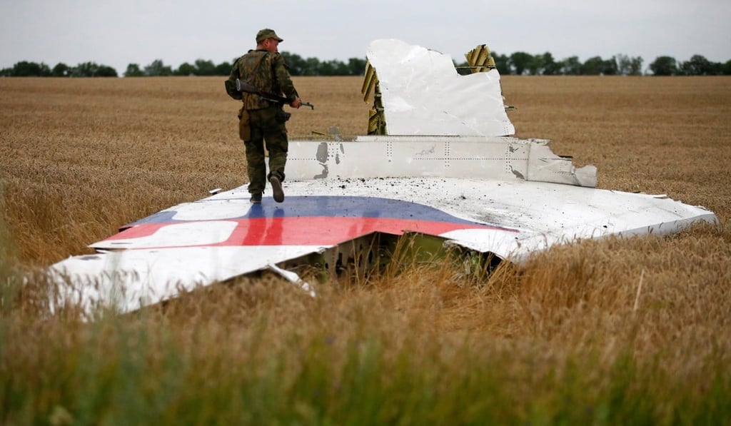 An armed pro-Russian separatist stands on part of the plane’s wreckage in 2014. Photo: Reuters