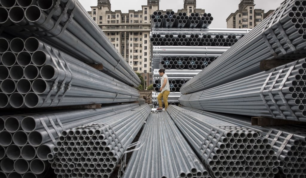 A worker walks over bundles of steel pipe stacked at a stockyard on the outskirts of Shanghai. Photo: Bloomberg