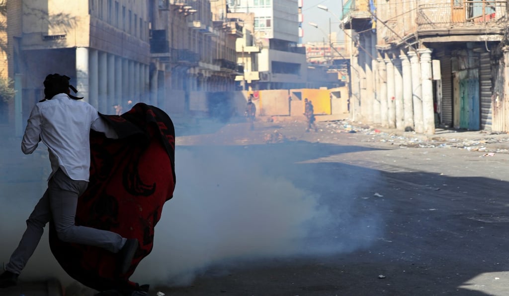 Iraqi riot police fire tear gas while blocking al-Rashid Street during clashes with anti-government demonstrators. Photo: AP Photo