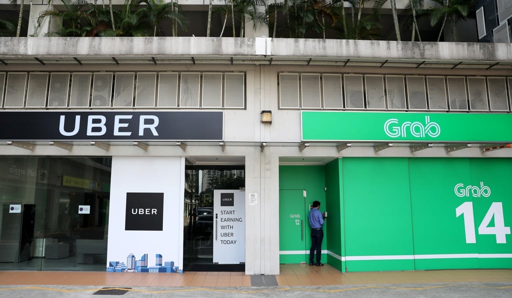 Signage for Uber and Grab are displayed outside a building in Singapore. Photo: Bloomberg
