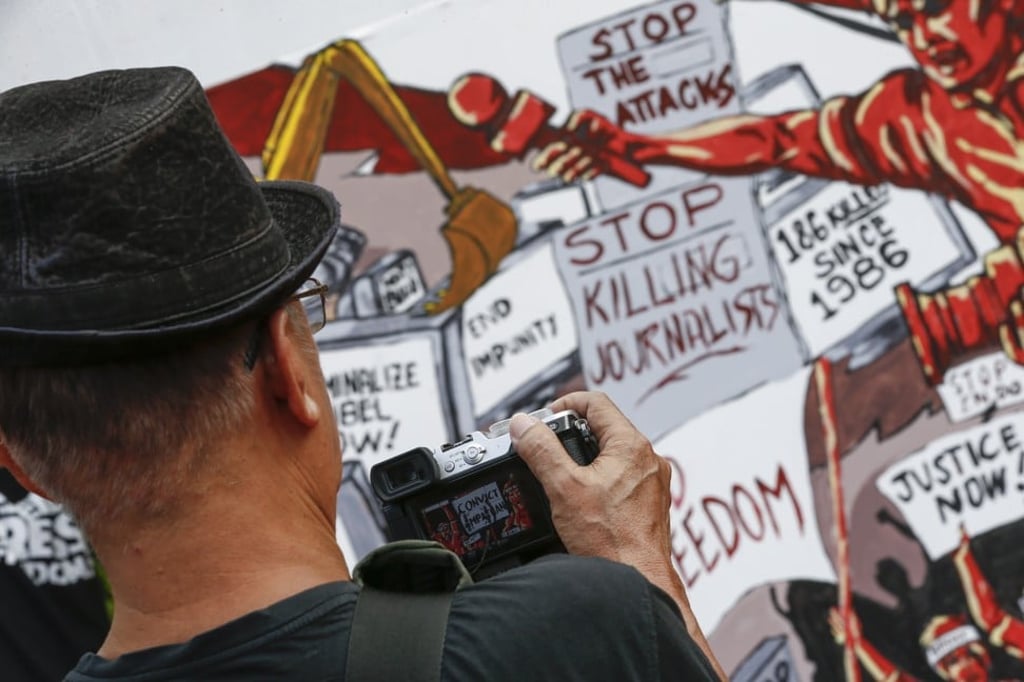 A man photographs a mural seen at the 10th-year commemoration of the Ampatuan Massacre in Manila, on November 23, 2019. Photo: EPA-EFE