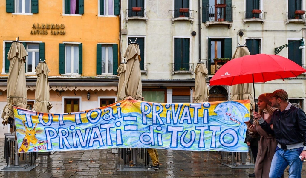 People walk past a banner reading ‘All in the hands of the private sector = Citizens deprived of everything’. Photo: AFP People walk past a banner reading ‘All in the hands of the private sector = Citizens deprived of everything’. Photo: AFP