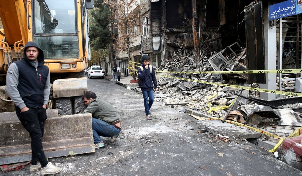 People walk near bank that was burned during protests against increased fuel prices in Tehran on November 20. Photo: West Asia News Agency via Reuters