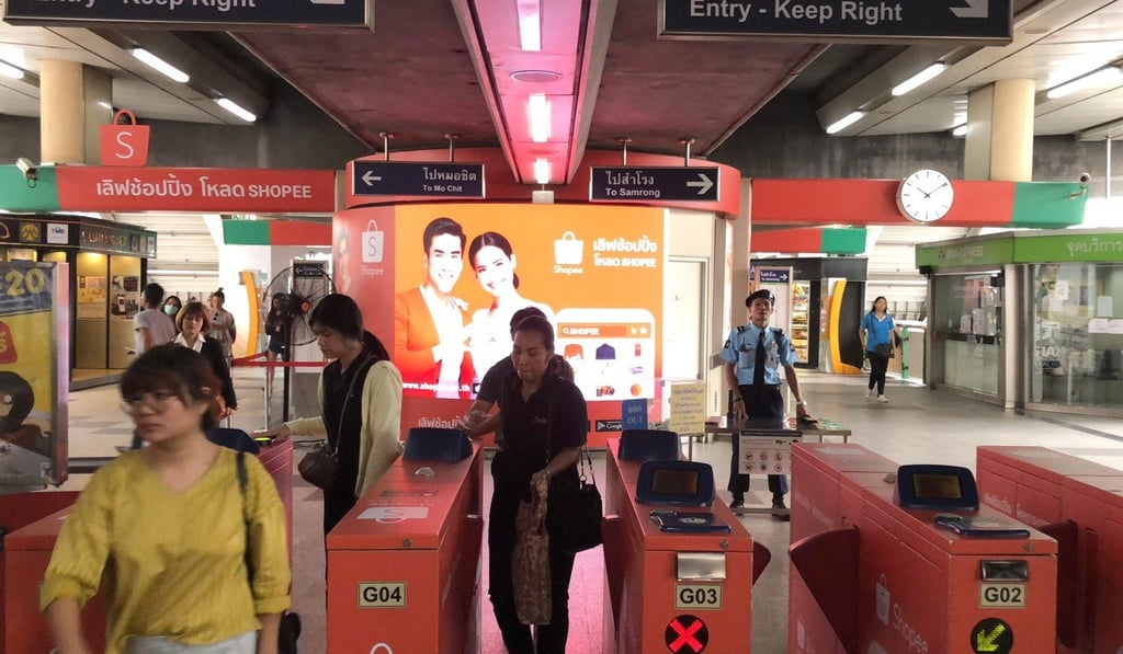 Commuters exit the gates at a Bangkok skytrain station with Shopee advertisement in background, 2018. Photo: SCMP
