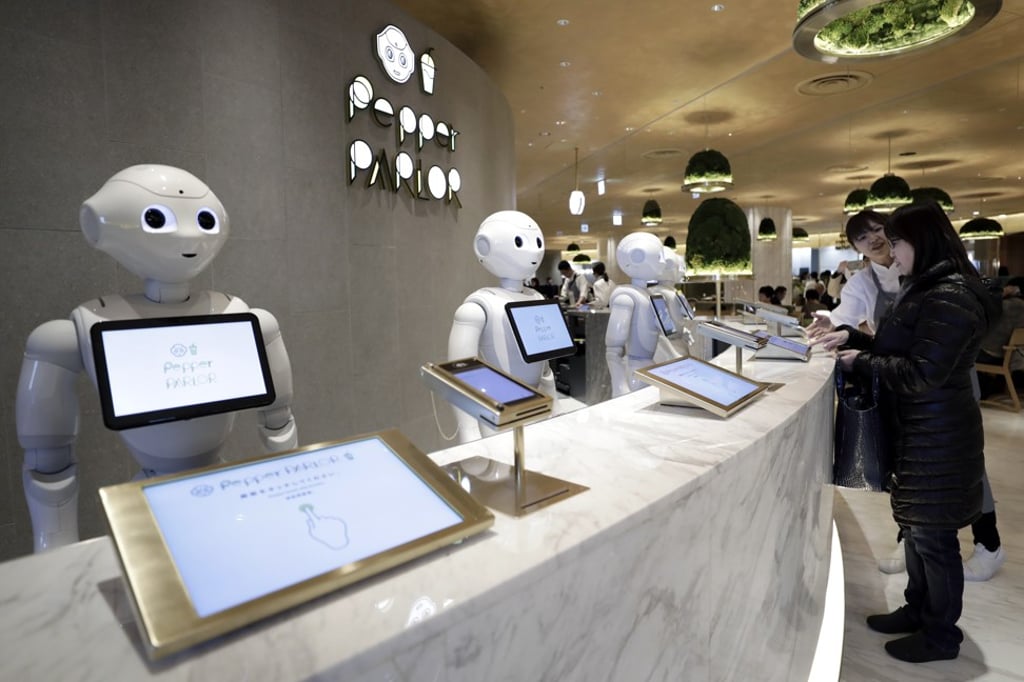 SoftBank Group Corp’s Pepper humanoid robots stand behind a counter, while a customer places an order at the company’s newly opened Pepper Parlor cafe inside the Tokyu Plaza Shibuya shopping complex in Tokyo on Thursday. Photo: Bloomberg