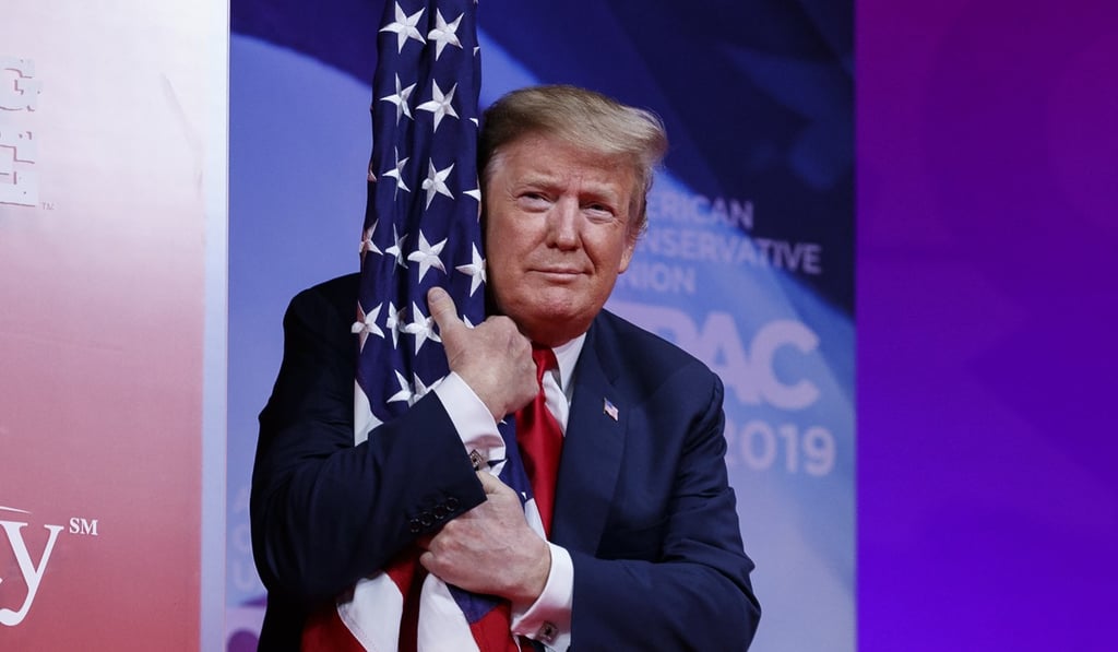 President Donald Trump hugs the American flag. Photo: AP President Donald Trump hugs the American flag. Photo: AP