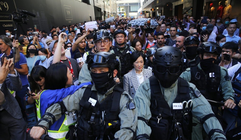 Prominent pro-Beijing lawmaker Regina Ip is escorted by police while surrounded by pro-democracy protesters and members of the media during a lunchtime anti-government rally in Central on November 25. Photo: EPA-EFE