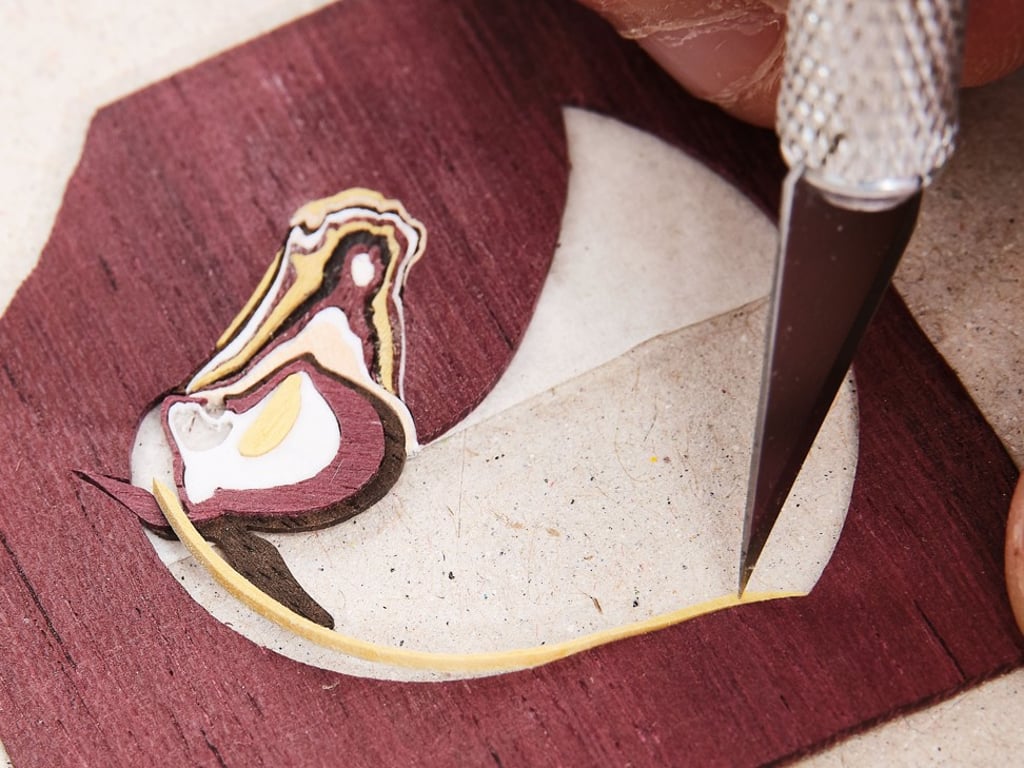 Once the craftsmen miniaturise the motif on the dial, they deftly cut out the tiny elements of wood forming the pattern. Once the craftsmen miniaturise the motif on the dial, they deftly cut out the tiny elements of wood forming the pattern.