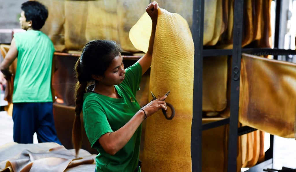 A woman cuts out stains from a raw rubber sheet at a factory in Thailand’s Rayong province in October 2018. Photo: AFP