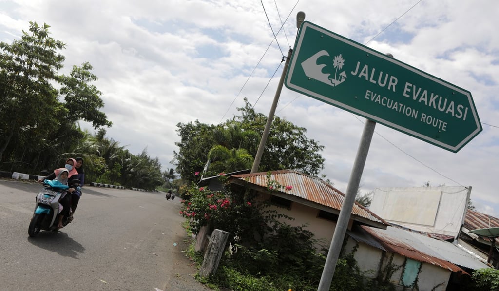 A woman rides a motorbike past a sign pointing at a tsunami evacuation route in Banda Aceh. Photo: EPA A woman rides a motorbike past a sign pointing at a tsunami evacuation route in Banda Aceh. Photo: EPA