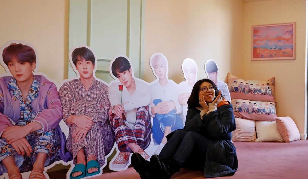 A K-pop fan poses for photographs with cut-out of BTS at a store in Seoul. Photo: Reuters