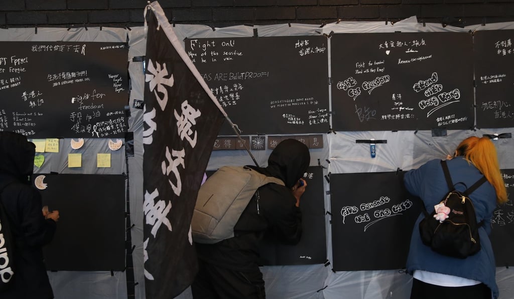The demonstrators signed their names on a memorial board that bore the names of 26 people who, they believed, had died during police operations or killed themselves over the ongoing social unrest. Photo: Winson Wong