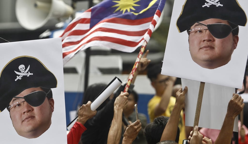 Protesters hold portraits of Malaysian fugitive Jho Low, the alleged mastermind behind the 1MDB money laundering and bribery scandal. Photo: AP