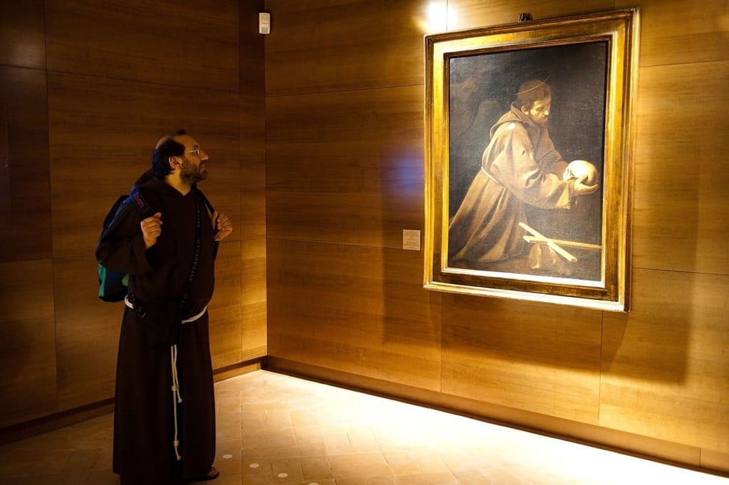 A Capuchin monk observes the Caravaggio painting St Francis in Meditation (1604-06) in the Capuchin Friars museum, Rome. Photo: Getty Images
