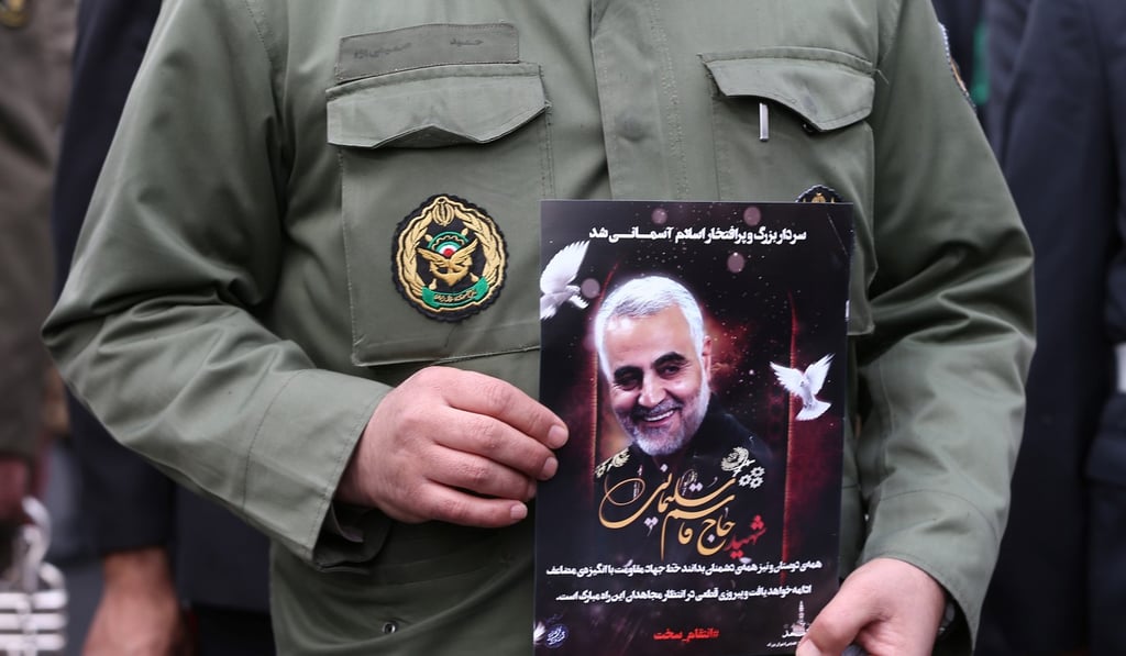 An Iranian policeman man holds a picture of late General Qassem Soleimani. Photo: Handout via Reuters