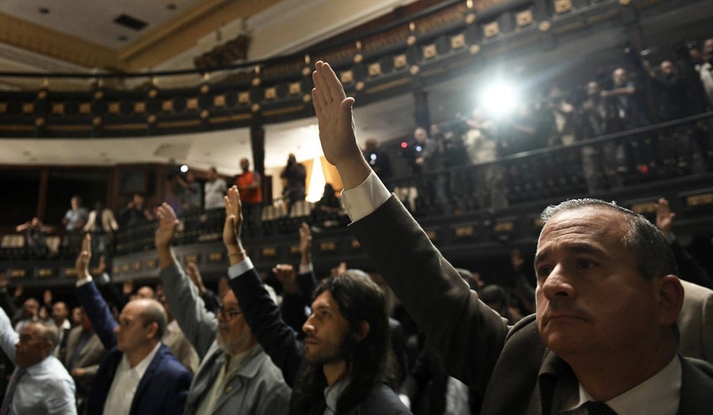 Lawmakers raise their hands to vote during a meeting at the chamber in Caracas, Venezuela, on Tuesday. Photo: Bloomberg