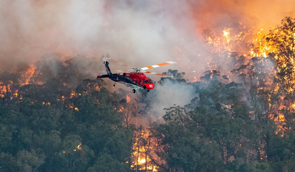 A firefighting helicopter in the East Gippsland region of Victoria. Photo: AAP/ DPA A firefighting helicopter in the East Gippsland region of Victoria. Photo: AAP/ DPA