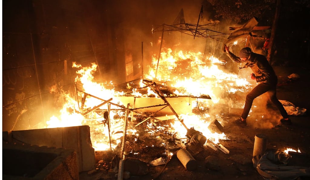 An anti-government protester tries to extinguishes a tent which set on fire during ongoing protests against the Lebanese political elites who have ruled the country since decades. Photo: AP