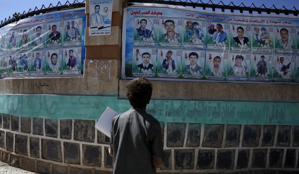 A boy stands in front of a wall with banners depicting portraits of late Houthi fighters allegedly killed in Yemen's ongoing conflict. Photo: EPA-EFE