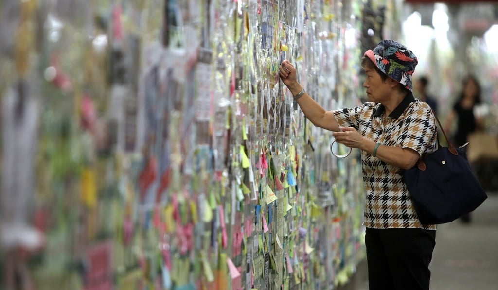 A woman looks at postings on a “Lennon Wall” in a pedestrian underpass outside Tai Po Market MTR station. Similar walls sprang up across the city, and became a battleground between protesters and government supporters. Photo: SCMP
