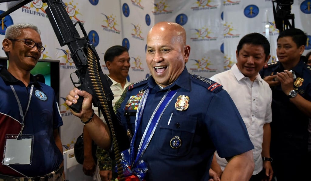 Philippine National Police chief Ronald dela Rosa holds an M60 machine gun during a gun show in Mandaluyong city in July 2017. Photo: Reuters