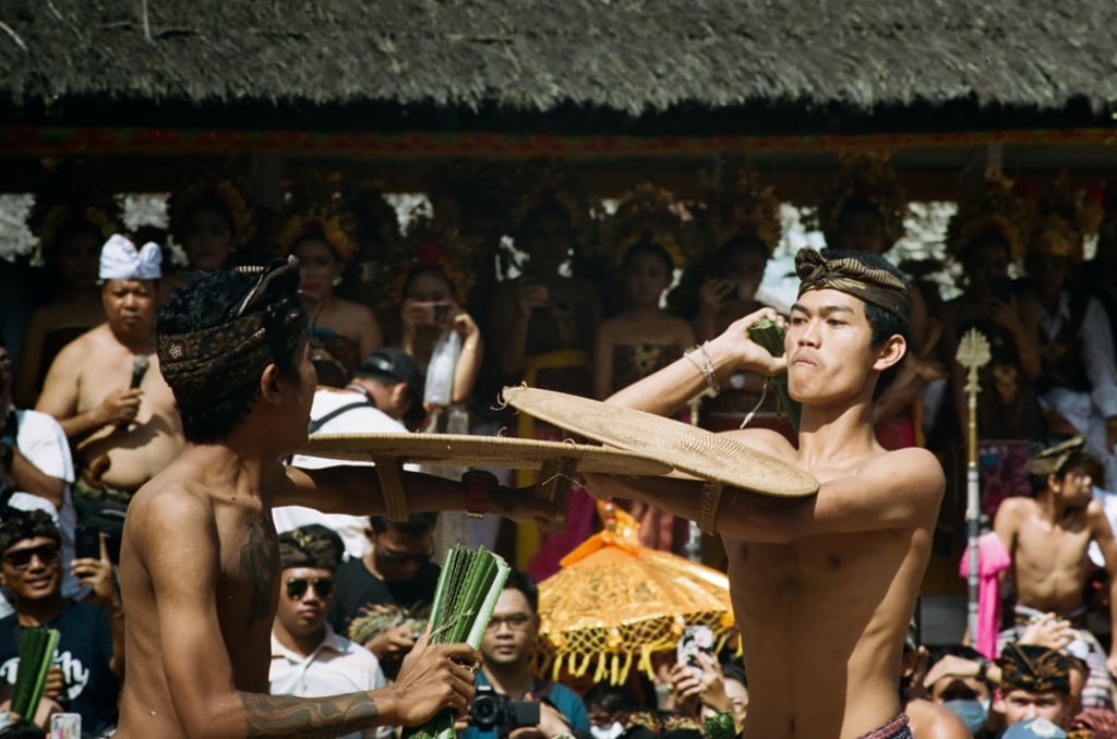 Two young men square off on a wooden stage while unmarried girls look on from the village hall in Tenganan. Photo: Daniel Darmawan
