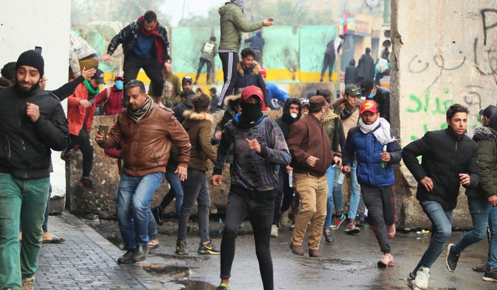 Anti-government protesters run during clashes with security forces in Baghdad. Photo: AP