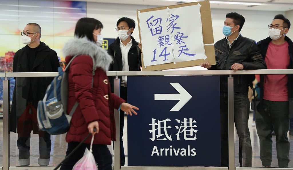 Pan-democratic lawmakers (from left) Shiu Ka-chun, Eddie Chu, Tam Man-ho and Alvin Yeung hold up a sign at the High Speed Rail West Kowloon Station on January 28, reminding arrivals from mainland China to stay at home for observation for 14 days. Photo: Winson Wong