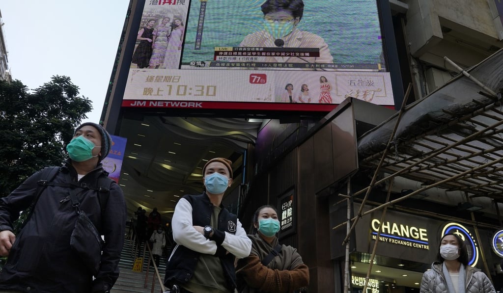 People wear face masks stand in front of a TV screen broadcasting Chief Executive Carrie Lam delivering a speech in Hong Kong. Photo: AP
