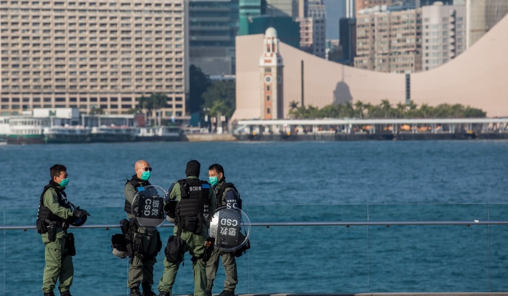 A group of Correctional Services Department officers wearing protective face masks stand on the waterfront outside government headquarters in Hong Kong. Photo: Bloomberg