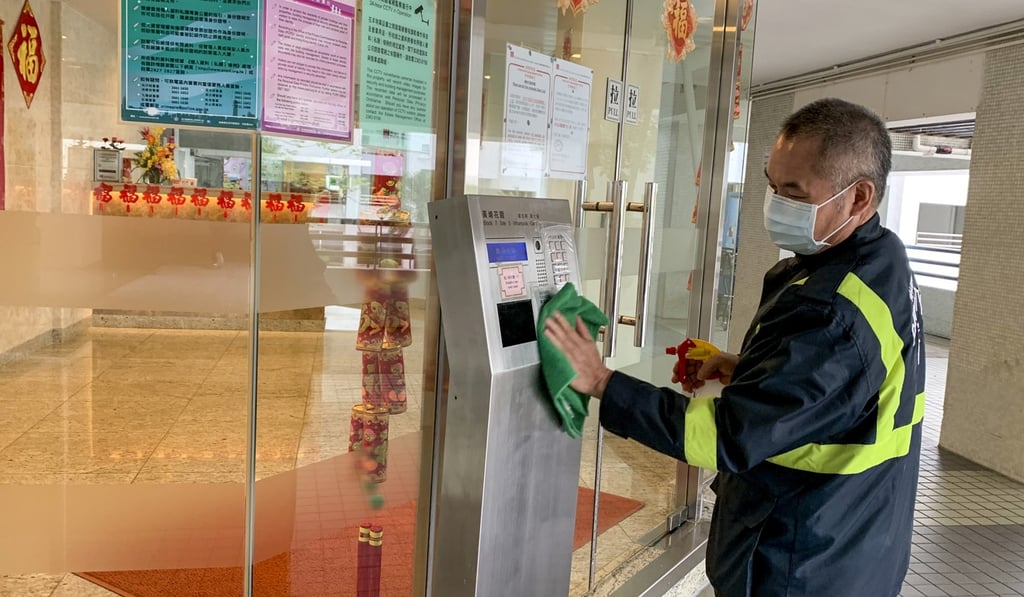 A security guard at Whampoa Garden applies disinfectant, something staff has been instructed to do to frequently touched surfaces every hour. Photo: Minnie Chan