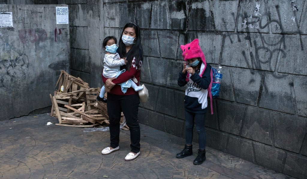 People wearing protective face masks stand on a pavement in Manila. Photo: Bloomberg People wearing protective face masks stand on a pavement in Manila. Photo: Bloomberg