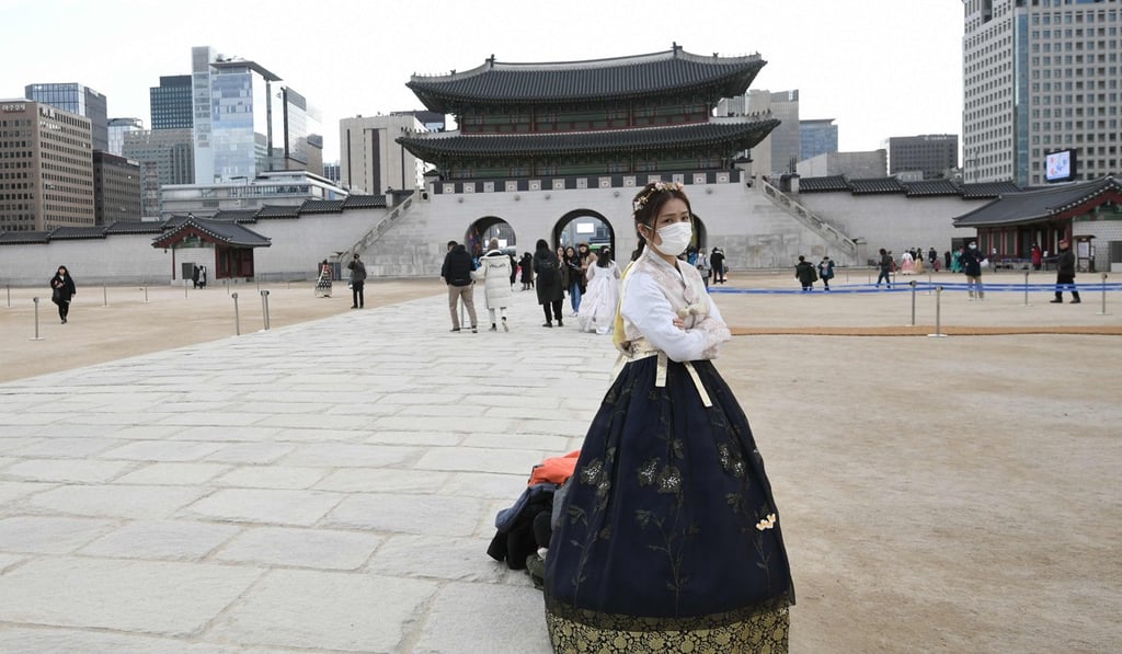 A woman in traditional Korean hanbok dress wears a face mask as she visits Gyeongbokgung Palace in Seoul. Photo: Jung Yeon-je/AFP