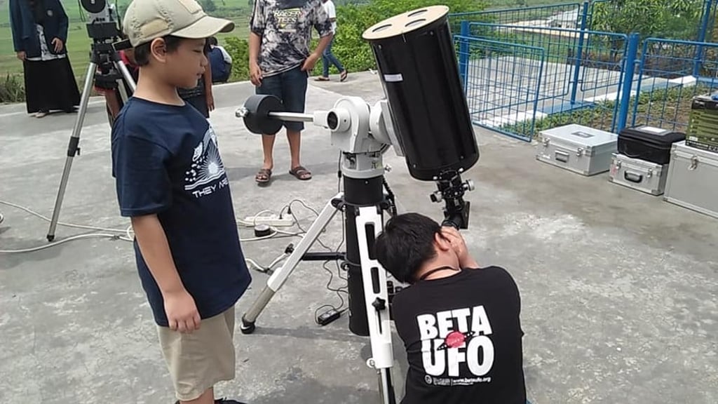 Children of Michael’s UFO research group members look through a telescope at a recent meet-up.