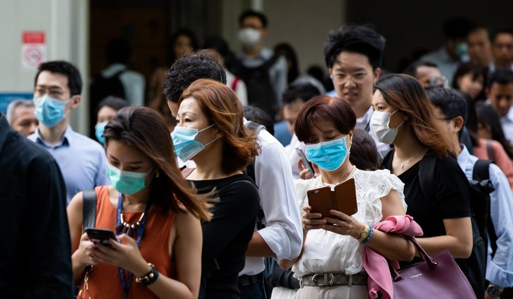 People in Singapore stand in line for a temperature check outside an office building in the central business district. Photo: Bloomberg