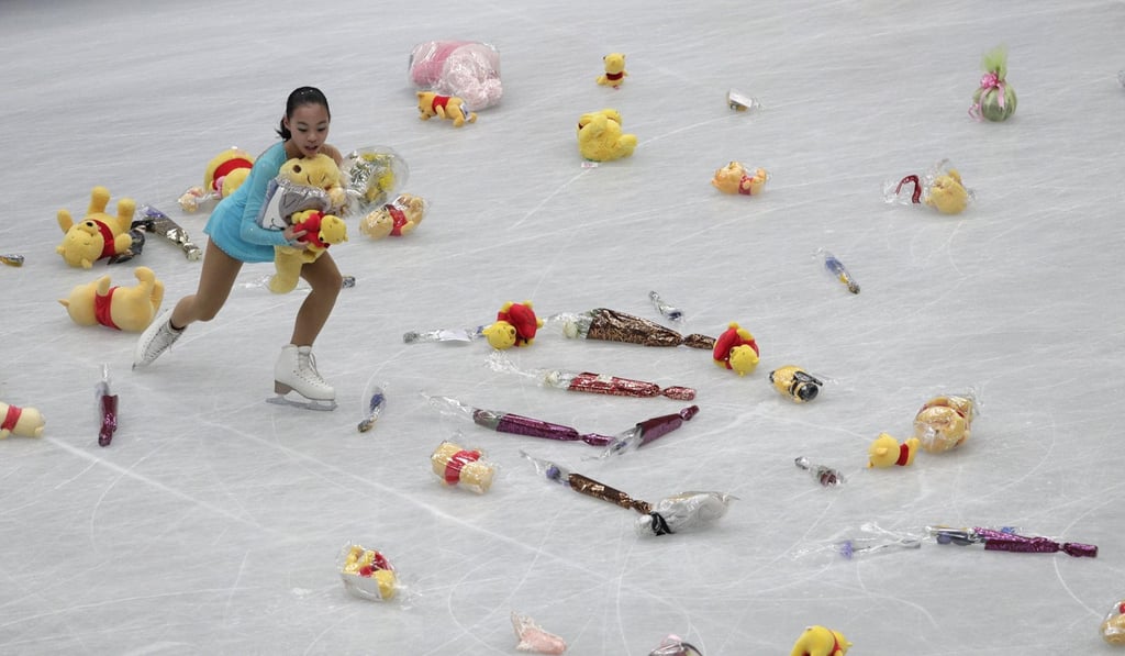 A young skater collects flowers and stuffed toys thrown on to the ice after Hanyu’s performance at the ISU World Figure Skating Championships in Japan in 2019. Photo: AP