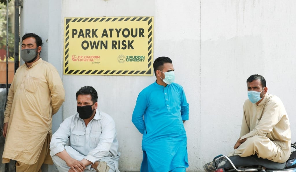 Men wearing face masks wait to see their relatives who were admitted after being affected by a suspected gas leak. Photo: Reuters