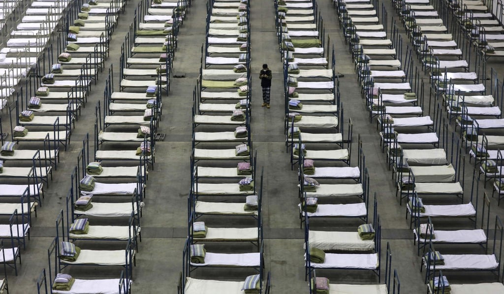 A worker walks among beds in a convention centre that has been converted into a temporary hospital in Wuhan. Photo: Chinatopix via AP