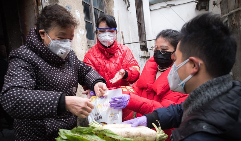 Community workers deliver food to an elderly woman in Wuhan. Tighter measures are making it harder to deliver the essentials. Photo: Xinhua