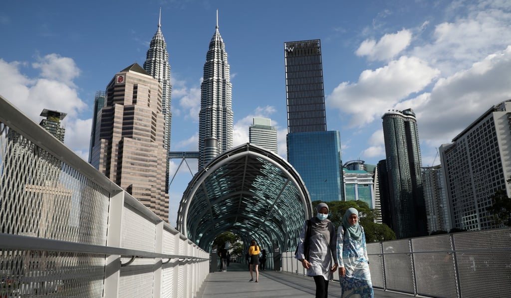 A woman wearing a protective face mask crosses a bridge in Kuala Lumpur, Malaysia. Photo: Reuters