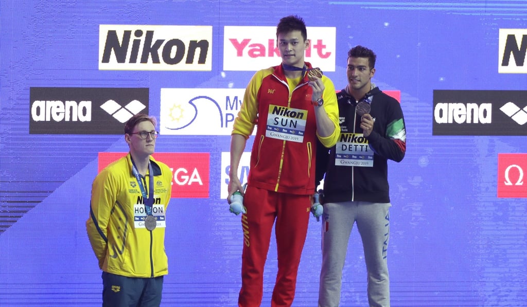 Sun Yang holds up his gold medal as silver medallist Mack Horton stands away from the podium. Photo: AP