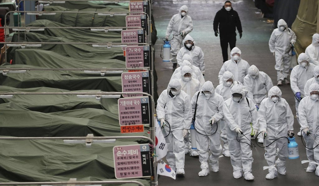 Market workers wearing protective gear spray disinfectant at a market in Daegu after a coronavirus outbreak in South Korea. Photo: AFP