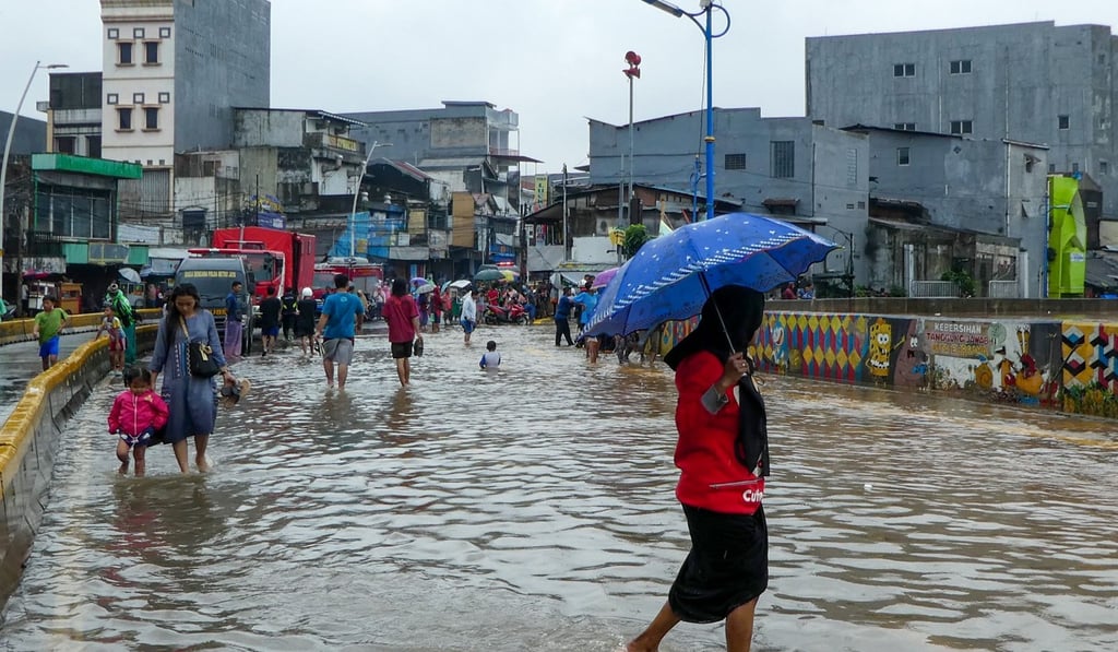 People walk through a flooded road after heavy rain. Photo: AFP