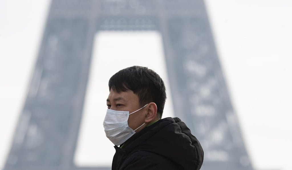 A tourist wearing a face mask walks past the Eiffel Tower in Paris. Photo: EPA