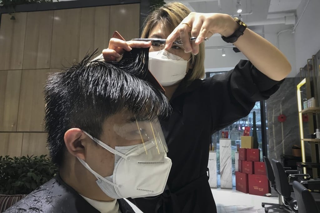 A barber wearing a protective face mask cuts a clients hair with an eye cover and face mask at a hair salon in Beijing. Photo: AP A barber wearing a protective face mask cuts a clients hair with an eye cover and face mask at a hair salon in Beijing. Photo: AP