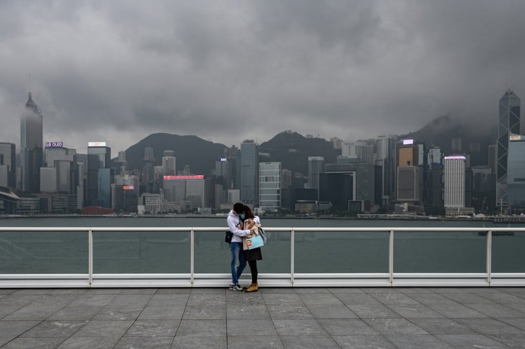 A couple wearing face masks hug each other on the waterfront at Tsim Sha Tsui, Hong Kong. Photo: AFP